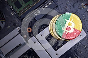 Golden bitcoins with flag of benin on a computer electronic circuit board. bitcoin mining concept
