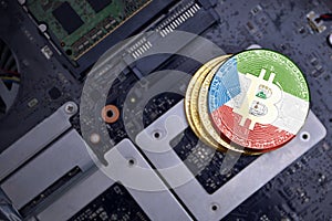 Golden bitcoins with flag of equatorial guinea on a computer electronic circuit board. bitcoin mining concept