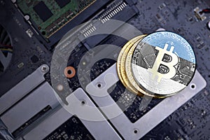 Golden bitcoins with flag of estonia on a computer electronic circuit board. bitcoin mining concept