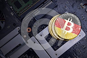 Golden bitcoins with flag of germany on a computer electronic circuit board. bitcoin mining concept