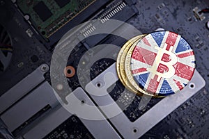 Golden bitcoins with flag of great britain on a computer electronic circuit board. bitcoin mining concept