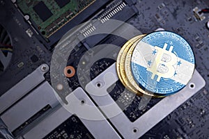 Golden bitcoins with flag of honduras on a computer electronic circuit board. bitcoin mining concept