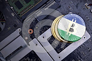 Golden bitcoins with flag of lesotho on a computer electronic circuit board. bitcoin mining concept