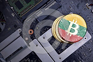 Golden bitcoins with flag of lithuania on a computer electronic circuit board. bitcoin mining concept