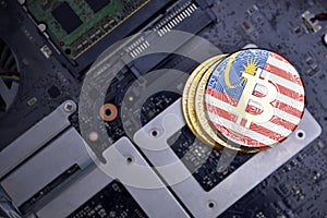 Golden bitcoins with flag of malaysia on a computer electronic circuit board. bitcoin mining concept