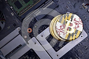 Golden bitcoins with flag of maryland state on a computer electronic circuit board. bitcoin mining concept