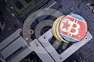 Golden bitcoins with flag of north korea on a computer electronic circuit board. bitcoin mining concept