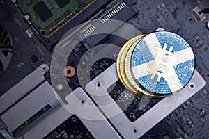 Golden bitcoins with flag of scotland on a computer electronic circuit board. bitcoin mining concept