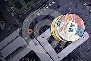 Golden bitcoins with flag of serbia on a computer electronic circuit board. bitcoin mining concept