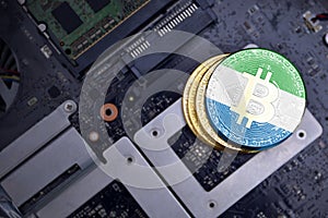 Golden bitcoins with flag of sierra leone on a computer electronic circuit board. bitcoin mining concept