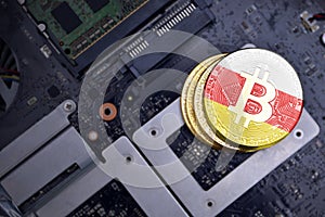 Golden bitcoins with flag of south ossetia on a computer electronic circuit board. bitcoin mining concept