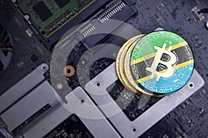 Golden bitcoins with flag of tanzania on a computer electronic circuit board. bitcoin mining concept