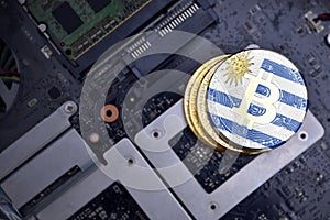 Golden bitcoins with flag of uruguay on a computer electronic circuit board. bitcoin mining concept