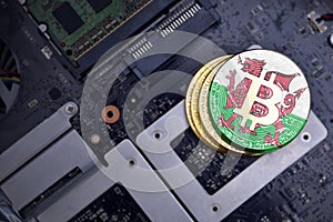 Golden bitcoins with flag of wales on a computer electronic circuit board. bitcoin mining concept