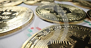 Golden bitcoins lie on papers with cryptocurrency charts