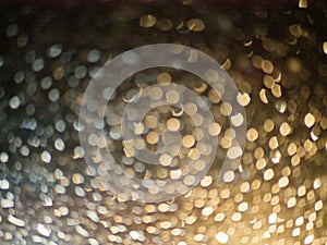 Golden black bokeh background of raindrops on a car windshield