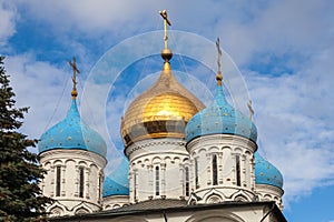 Golden and blue domes of an Orthodox church on a background of blue sky with white clouds