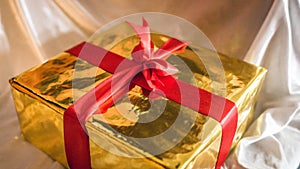 Golden box of present with red ribbon