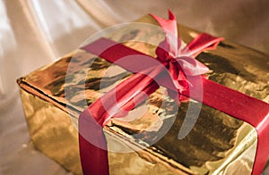 Golden box of present with red ribbon