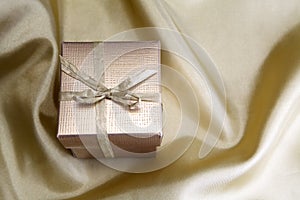 Golden box with ribbon on golden silk