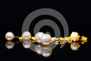 Golden bracelet and earstuds with white pearls in it