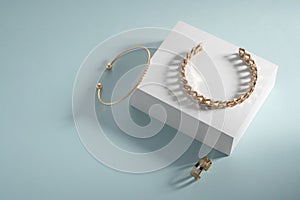 Golden bracelets and ring on white box on blue background