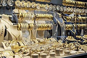 Golden bracelets on a shelf on a showcase of goldsmith, close up