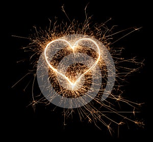 Golden bright sparkler heart shape love shaped symbol isolated dark black background. silvester new year birthday wedding and