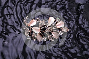 Golden brooch twig with moonstones and diamonds in the water