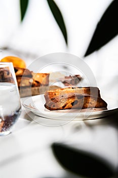 Golden-Brown Almond, Hazelnut and Cranberry Biscotti Slices on Elegant White Plate, Illuminated by Natural Light on