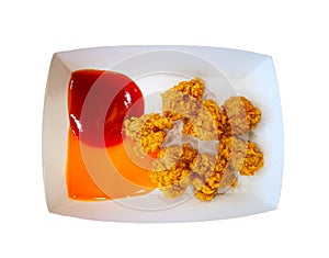 Golden brown fried chicken in small pieces on square white paper plate with Tomato ketchup and chili sauce isolated on white backg