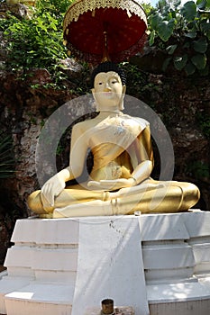 Golden Buddha image, sacred belief in Thai temple located on high mountain, forest and sky background.