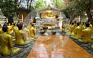 Golden Buddha and monks statues in Buddhist temple