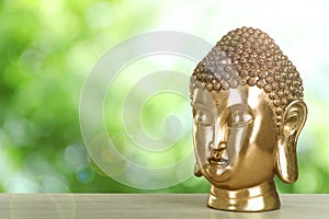 Golden Buddha sculpture on wooden table outdoors. Space for text