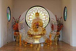 Golden Buddha sitting with hands clasped in contemplation on the