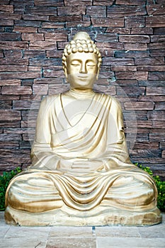 Golden Buddha statue against a brick wall background