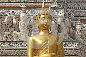 Golden buddha statue with background of decorative figures on stupa in Wat Arun. Bangkok, Thailand