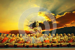 golden buddha statue in buddhism temple thailand against dramatic sun rising with ray beam background