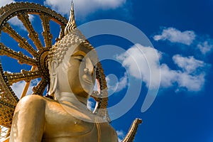 Golden Buddha Statue in a Buddhist temple in Thailand against the blue sky. Buddha and the wheel of Dharma. Statue of a