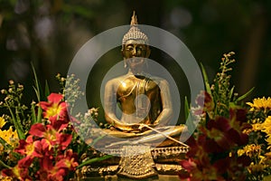Golden buddha statue flanking with flowers photo