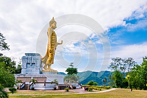 Golden Buddha statue standing on top of mountain.