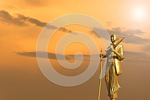 Golden Buddha statue on sunset sky background