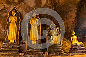 Golden buddha statues along the wall inside the cave