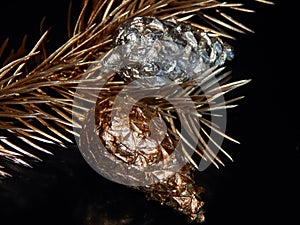 Golden bump on a golden branch of a Christmas tree on a black background