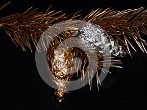 Golden bump on a golden branch of a Christmas tree on a black background