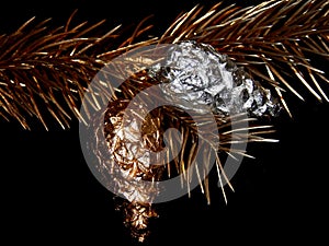 Golden bump on a golden branch of a Christmas tree on a black background