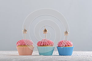 Golden candles in the shape of star on cupcakes with pink buttercream frosting. Birthday cupcakes. Party food