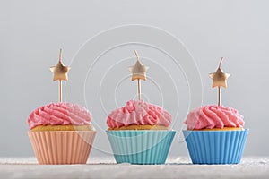 Golden candles in the shape of star on cupcakes with pink buttercream frosting. Birthday cupcakes. Party food. Close up