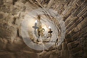 golden candlestick with two candles on the antique stone wall of the castle