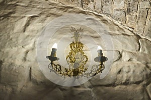 golden candlestick with two candles on the antique stone wall of the castle